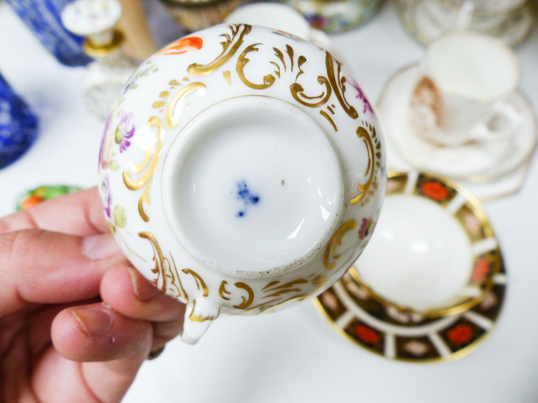 A group of Dresden and Continental porcelain cups and saucers boxes and covers and a scent bottle, 14 cm high